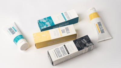 Assortment of Schmidt's toothpastes laying on white background, three in packaging boxes, two unboxed in tubes